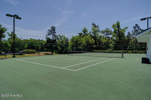 view of tennis court with community basketball court and fence