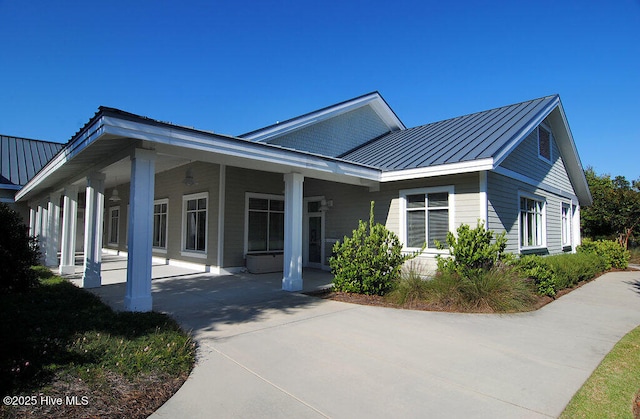 view of front of house featuring concrete driveway, a standing seam roof, and metal roof