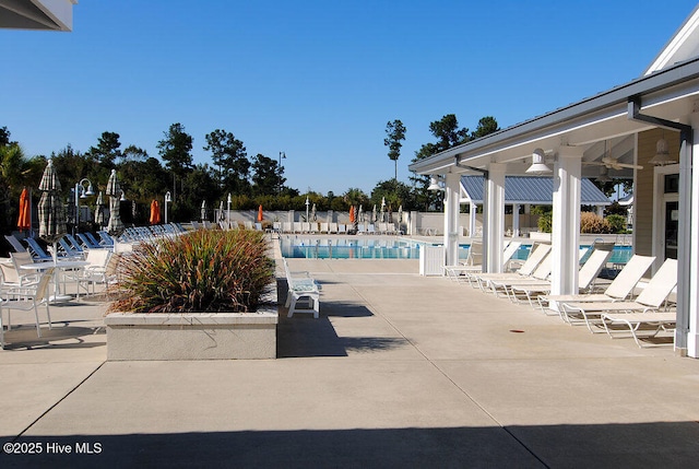 community pool with a patio, fence, and a ceiling fan