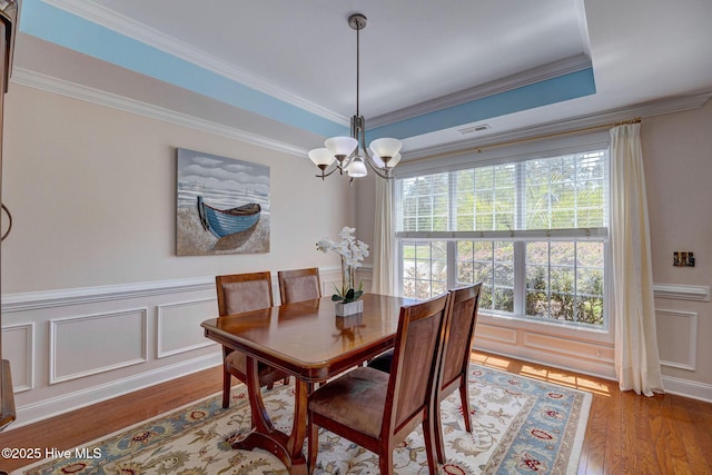 dining room with crown molding, an inviting chandelier, wood finished floors, and visible vents