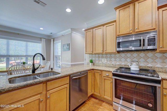 kitchen featuring light stone countertops, appliances with stainless steel finishes, a sink, visible vents, and ornamental molding