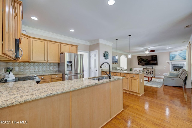 kitchen with a peninsula, open floor plan, ceiling fan, a sink, and appliances with stainless steel finishes