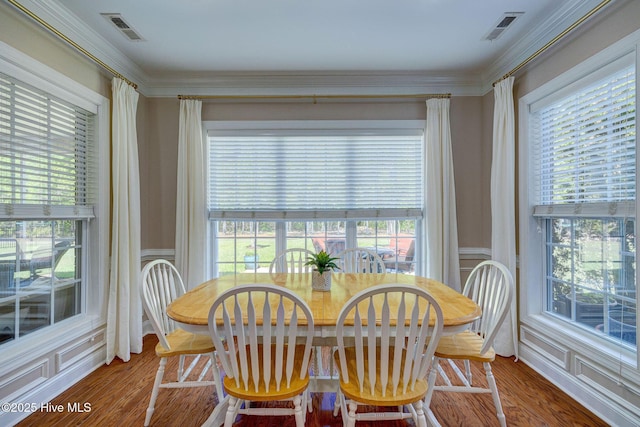 dining space with visible vents, crown molding, and wood finished floors