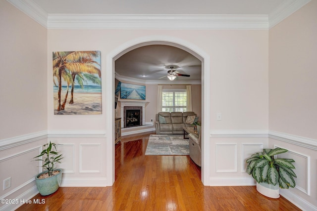 corridor with crown molding, wainscoting, and wood finished floors
