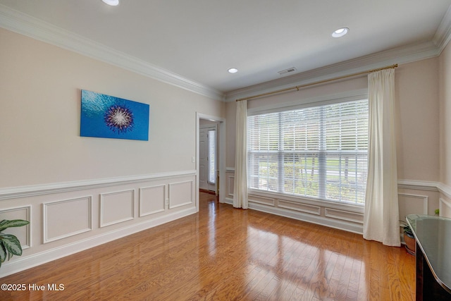 unfurnished room with visible vents, ornamental molding, wood finished floors, a decorative wall, and recessed lighting