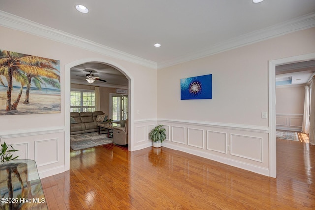 interior space with ornamental molding, ceiling fan, wood finished floors, and a decorative wall