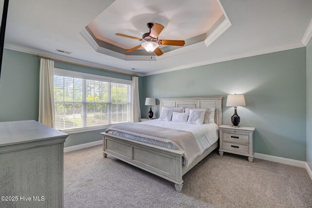 bedroom with visible vents, crown molding, baseboards, light colored carpet, and a raised ceiling