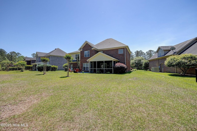 rear view of house featuring a yard, a sunroom, and brick siding