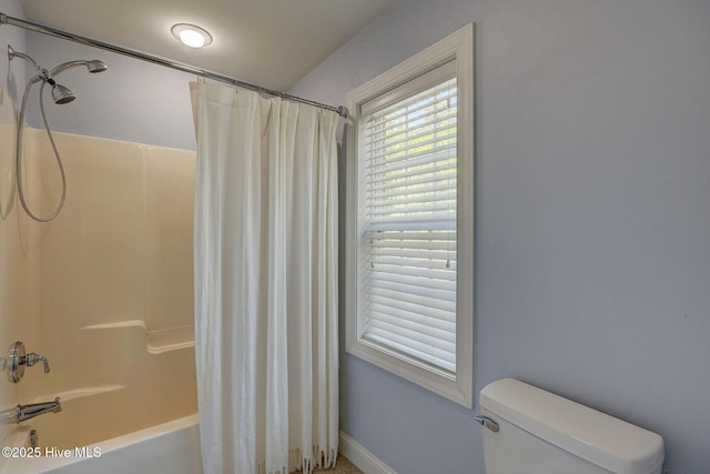 bathroom with baseboards, shower / bath combo, and toilet