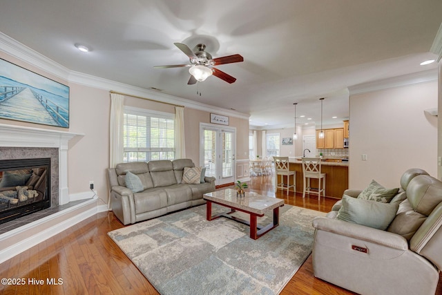 living area with ornamental molding, light wood finished floors, and ceiling fan