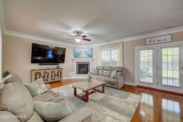 living area featuring ceiling fan, visible vents, ornamental molding, and hardwood / wood-style flooring