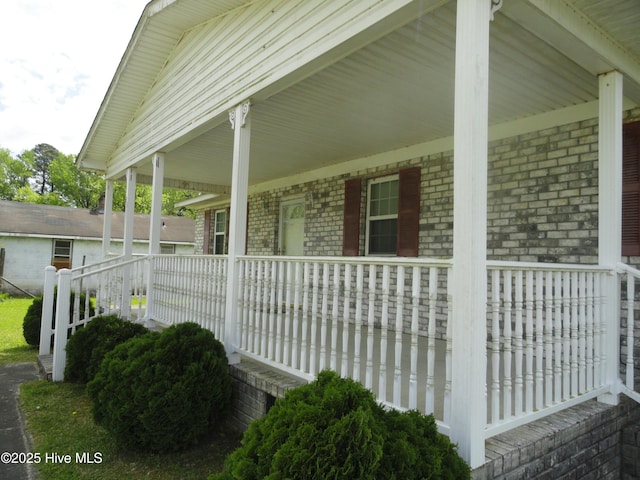 view of side of property featuring brick siding and covered porch