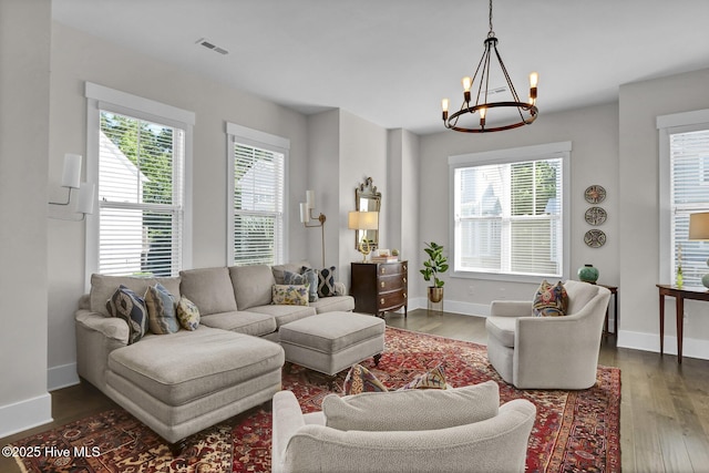 living room featuring an inviting chandelier, baseboards, dark wood-type flooring, and visible vents