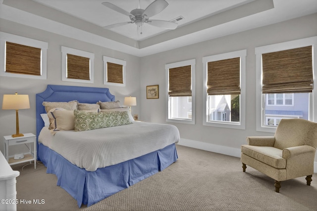 carpeted bedroom featuring baseboards, ceiling fan, a raised ceiling, and visible vents