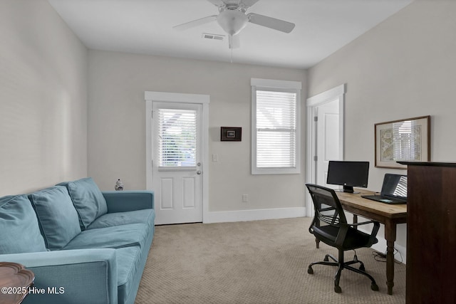 home office with light colored carpet, ceiling fan, visible vents, and baseboards