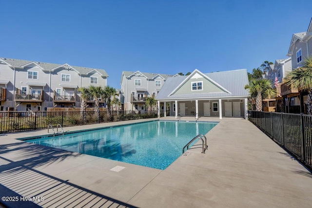 pool with a patio, fence, and a residential view