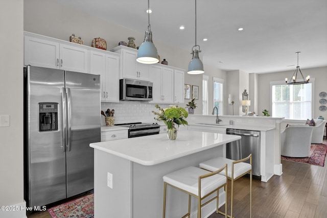 kitchen featuring a sink, appliances with stainless steel finishes, a peninsula, and light countertops