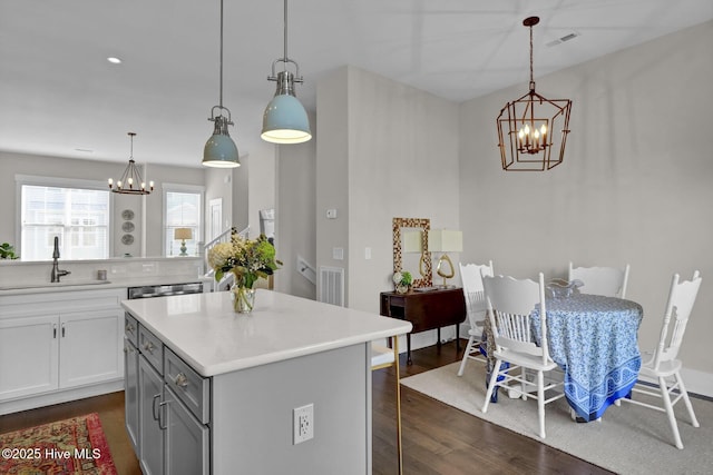 kitchen featuring a chandelier, a sink, dark wood-type flooring, and a kitchen bar