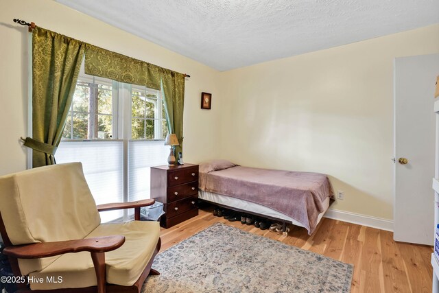 bedroom with baseboards, wood finished floors, and a textured ceiling
