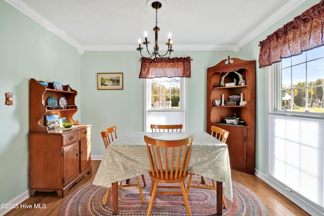 dining room with light wood-type flooring, plenty of natural light, a chandelier, and ornamental molding