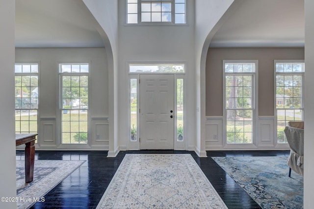 7240 Orchard Trce, Wilmington, NC 28409 - foyer entrance featuring arched walkways, wainscoting, a decorative wall, and dark wood finished floors