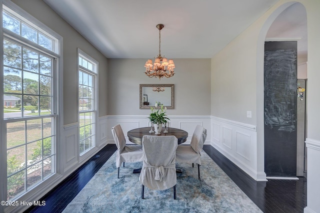 7240 Orchard Trce, Wilmington, NC 28409 - dining room featuring a wainscoted wall, arched walkways, dark wood-type flooring, a decorative wall, and a notable chandelier