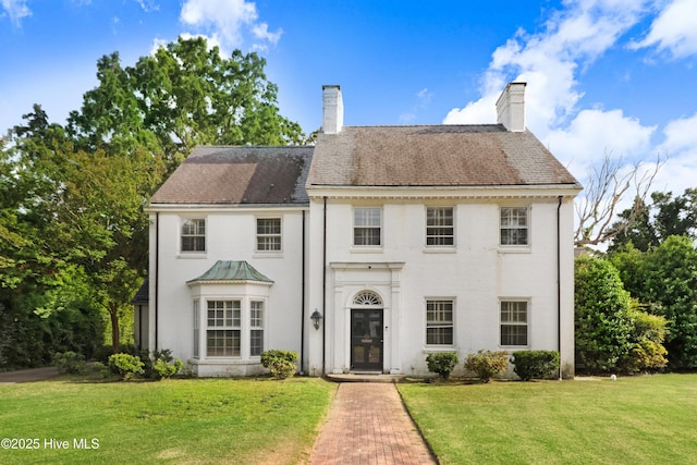 view of front of property featuring stucco siding, a chimney, and a front yard