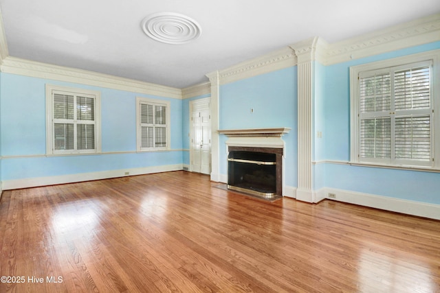 unfurnished living room featuring a healthy amount of sunlight, a fireplace with flush hearth, and wood finished floors