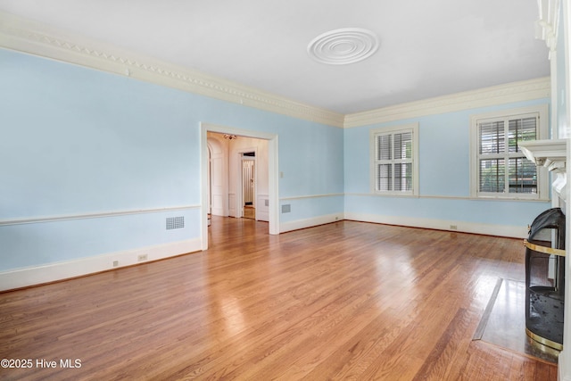 unfurnished living room with baseboards, crown molding, visible vents, and wood finished floors