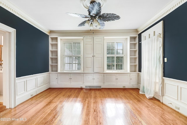 spare room with ceiling fan, ornamental molding, a decorative wall, and light wood-style floors