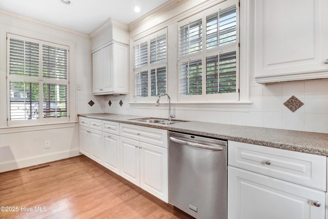 kitchen featuring light wood finished floors, decorative backsplash, stainless steel dishwasher, and a sink