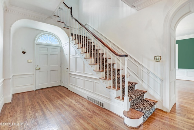 foyer featuring wood finished floors, visible vents, a decorative wall, and arched walkways