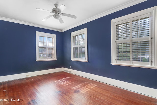 empty room with wood finished floors, ornamental molding, visible vents, a ceiling fan, and baseboards
