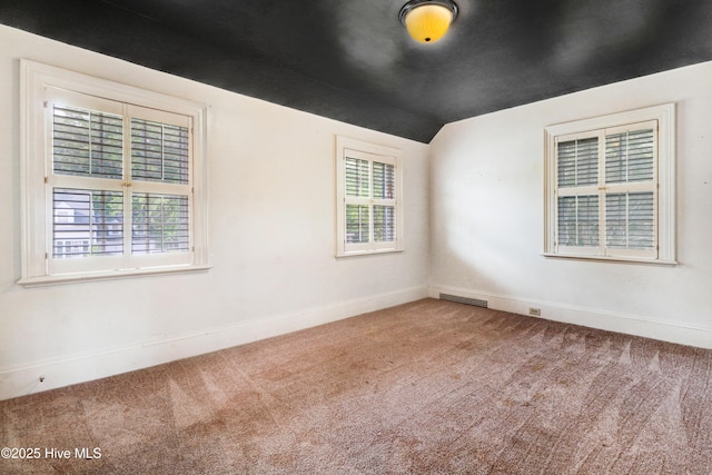 unfurnished room featuring lofted ceiling, carpet flooring, visible vents, and baseboards