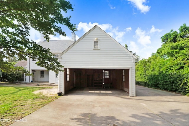 view of property exterior with a yard, concrete driveway, a garage, and a chimney
