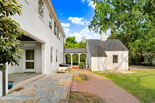 exterior space with central AC, a chimney, an outdoor structure, a yard, and a patio area