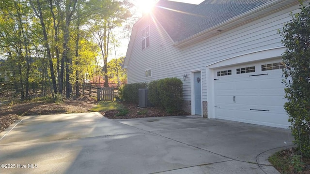 112 Schever Rd, West End, NC 27376 - view of side of property with a garage, concrete driveway, central air condition unit, and a shingled roof