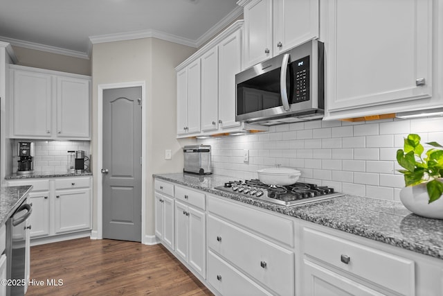 kitchen with appliances with stainless steel finishes, white cabinetry, ornamental molding, and backsplash