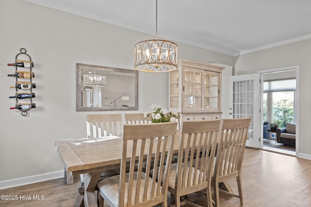 dining space featuring a chandelier, crown molding, wood finished floors, and baseboards