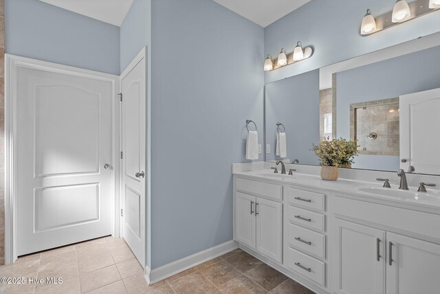 full bath featuring a walk in shower, baseboards, double vanity, and tile patterned flooring