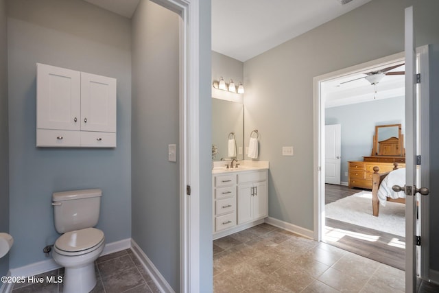 ensuite bathroom featuring baseboards, toilet, and vanity