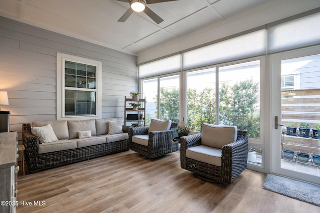 sunroom with outdoor lounge area, a ceiling fan, wood finished floors, wood walls, and a wooden deck