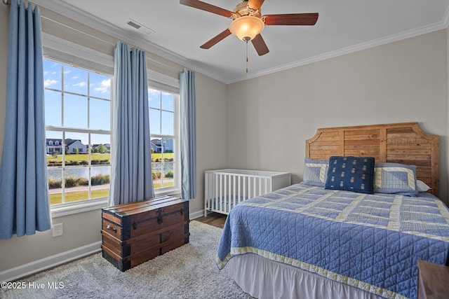 bedroom with baseboards, crown molding, a ceiling fan, carpet floors, and a water view