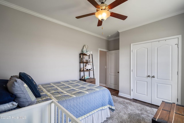 bedroom with ornamental molding, wood finished floors, baseboards, a closet, and a ceiling fan