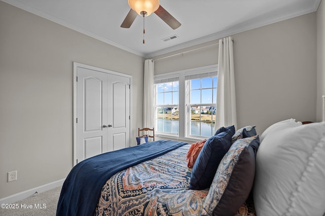 carpeted bedroom featuring a water view, baseboards, crown molding, a closet, and a ceiling fan