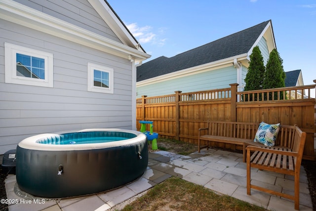 view of patio with a hot tub and fence
