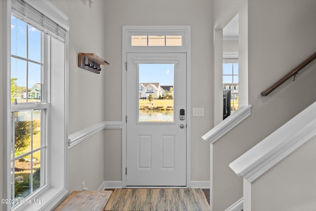 entryway featuring baseboards, wood finished floors, and stairs