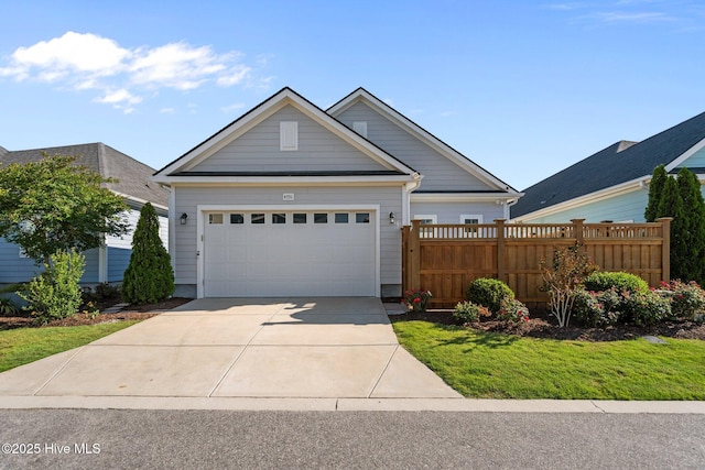 view of front of house with a garage, concrete driveway, and fence
