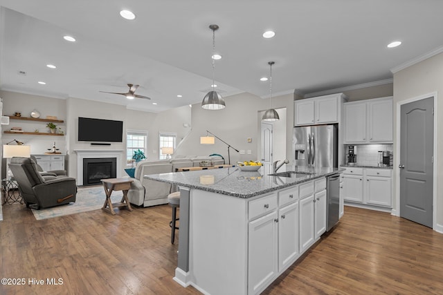 kitchen with stainless steel appliances, a sink, ornamental molding, ceiling fan, and dark wood-style flooring