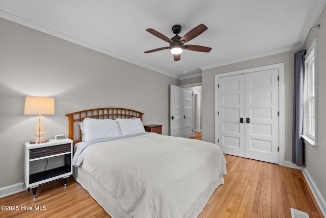 bedroom with light wood-style floors, baseboards, crown molding, and a closet